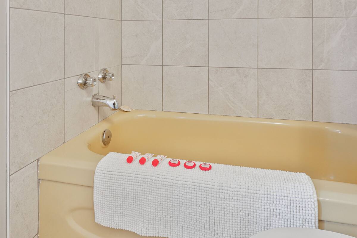 A bathtub with a white towel and red bath products.