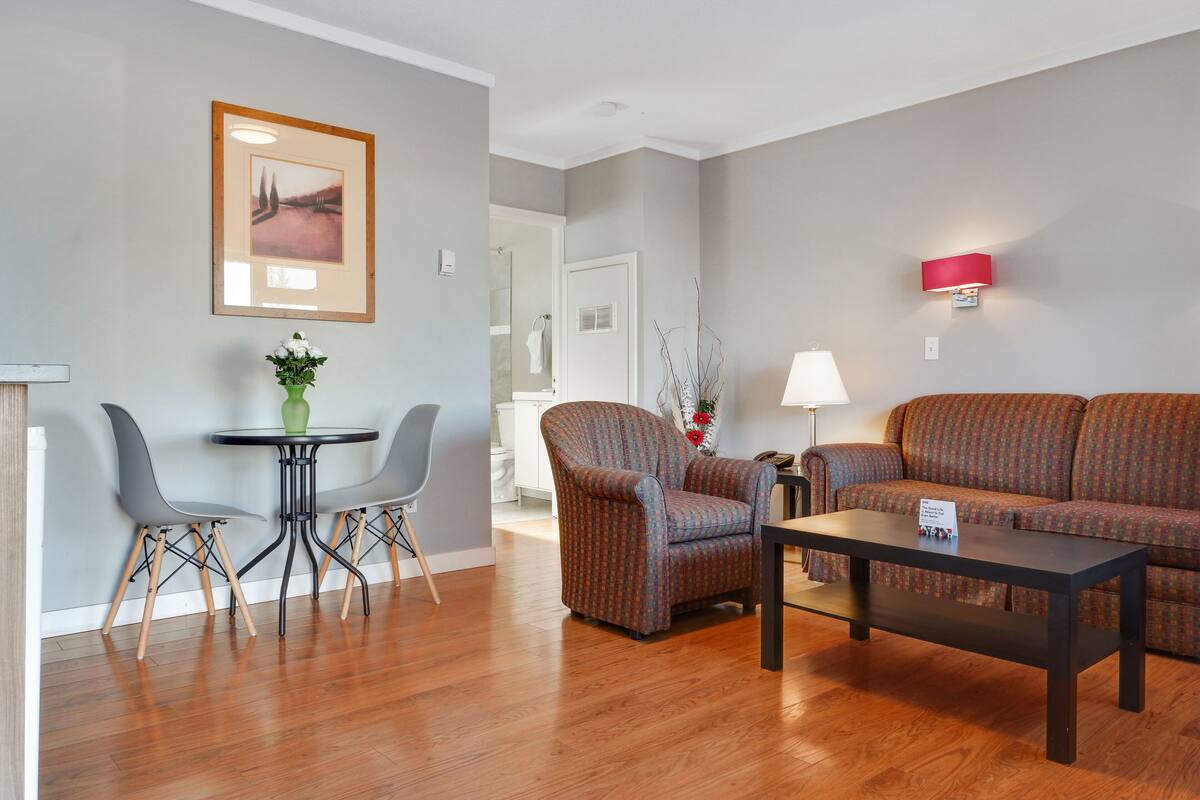 A modern living room with a sofa, two armchairs, a coffee table, and a dining table with chairs.