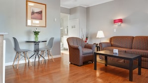 A modern living room with a sofa, two armchairs, a coffee table, and a dining table with chairs.