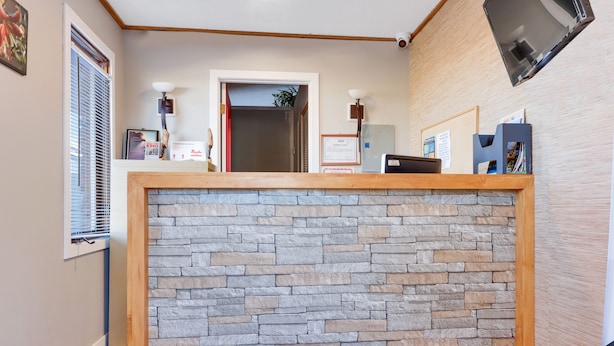 A reception area with a stone wall, wooden reception desk, framed certificates, and a door leading to another room.