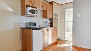 A compact kitchen with wooden cabinets, a white refrigerator, a microwave, and a coffee maker.