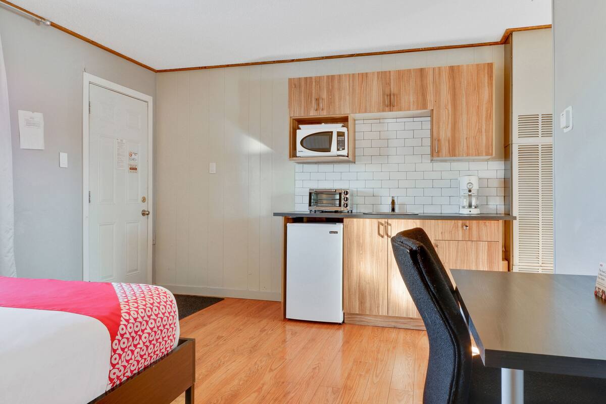 A compact kitchen with wooden cabinets, a microwave, a toaster, and a refrigerator.