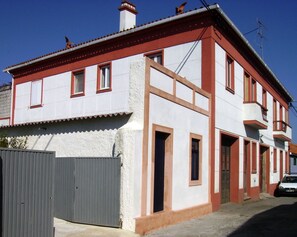 Un bâtiment à deux étages, doté d’une façade rouge et blanche, de nombreuses fenêtres et d’une porte de garage bien visible.