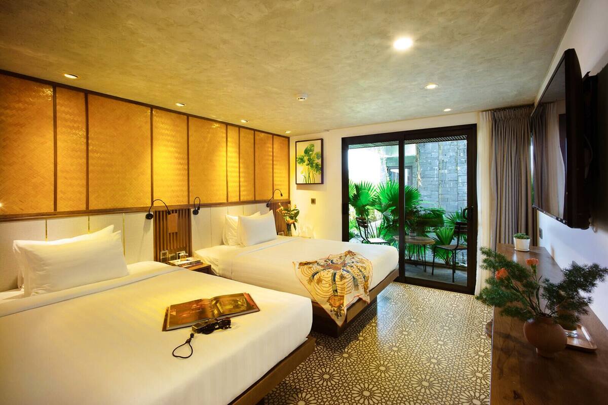 A hotel room with two beds, a large window, and a view of the outdoors.