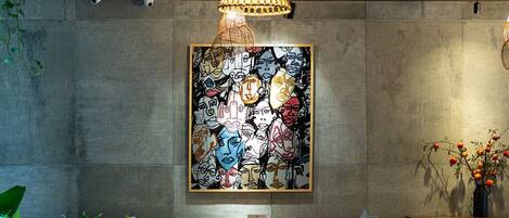 A restaurant with wooden tables and chairs, a large abstract painting on the wall, and a hanging light fixture.