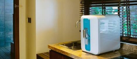 A kitchen with a water dispenser, wooden cabinets, and a tiled floor.