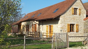 A stone building with a sloped roof and wooden shutters, surrounded by a gravel area and a wooden fence. - "Les Vieux Poiriers" (near Taize, Cluny ..) in Bonnay 71460 (Cluniac site) (Bonnay)