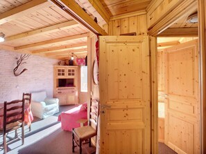 Relax in a spacious room with a comfortable seating area, large double door, and exposed wooden beams.