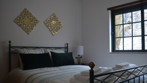 Una cama bien tendida con ropa de cama a rayas y dos elementos decorativos en la pared.