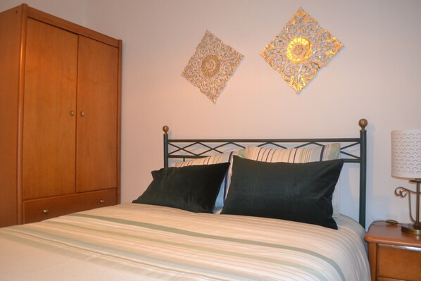 Un dormitorio con cama, armario de madera, mesita de noche y decoración mural.