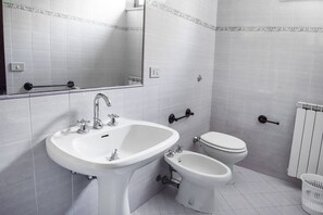 Ein Badezimmer mit Waschbecken, Bidet, Toilette und Spiegel.