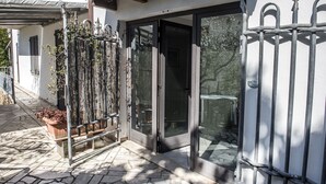 A house with a stone-paved entrance, a metal gate, and a sliding glass door.