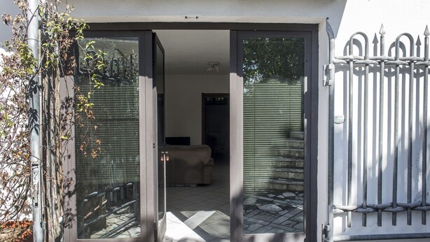 A sliding glass door leading to a room with a tiled floor and a sofa.