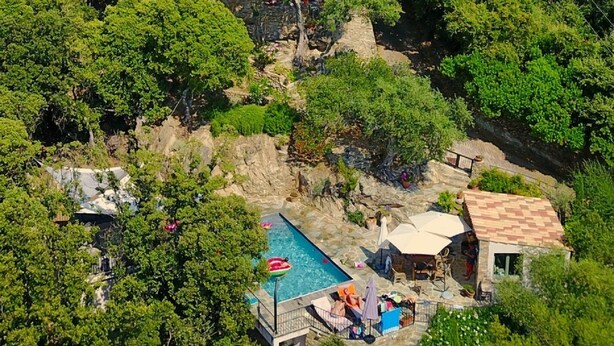 Ein Steinhaus mit Pool und Außenbereich, umgeben von üppigem Grün.