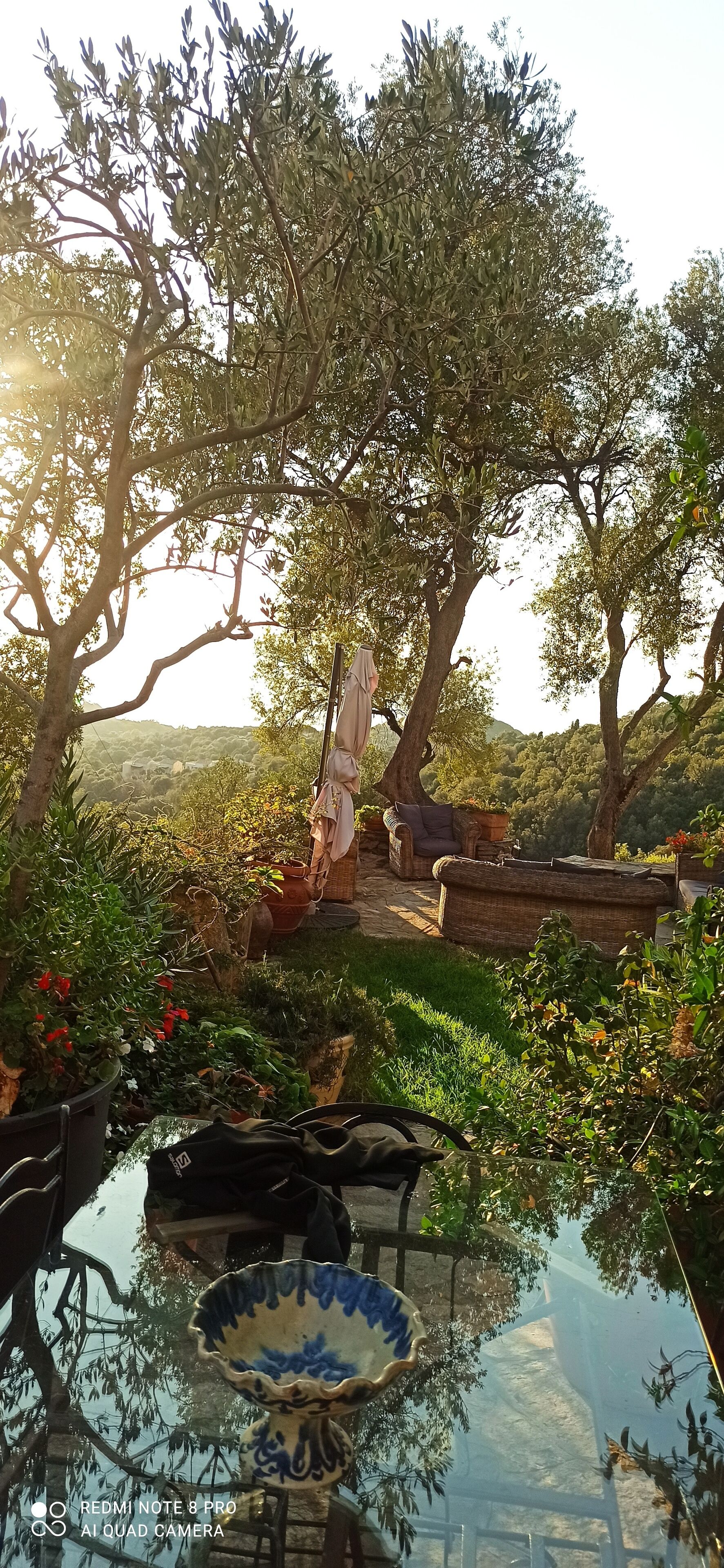 Un espace extérieur aménagé avec une table en verre, des chaises et un vase décoratif.