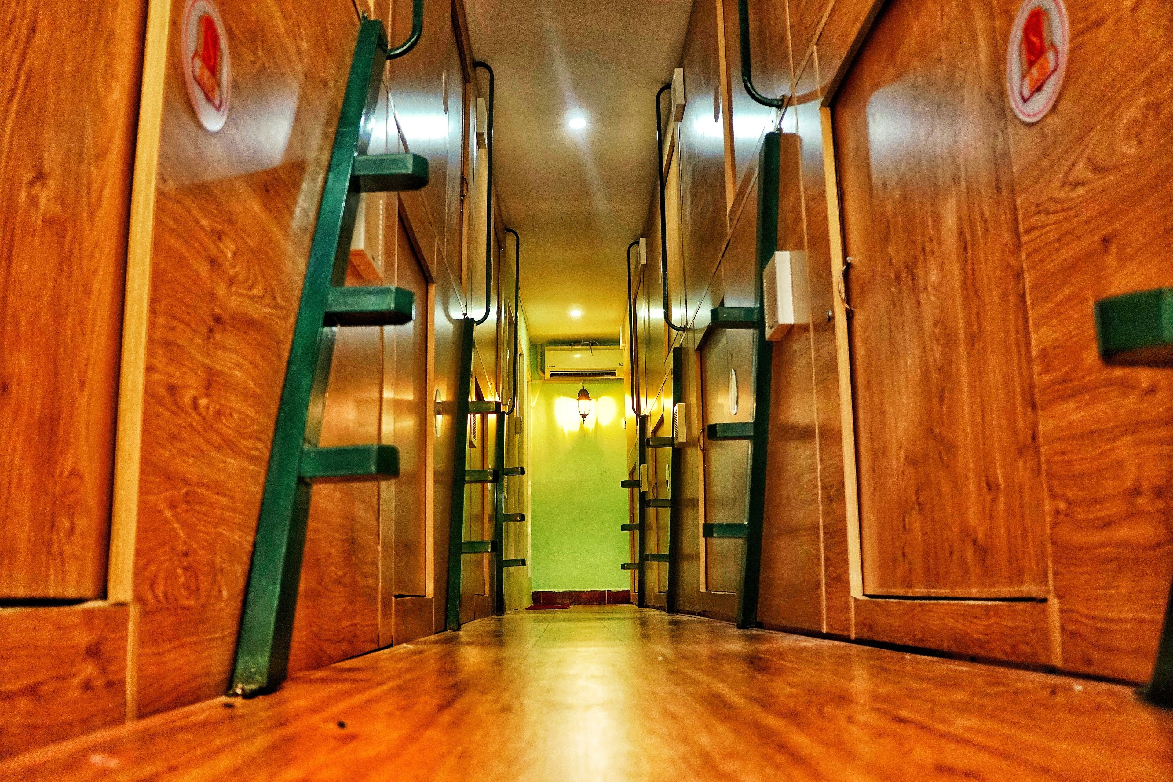 Un couloir aux murs en bois et une échelle verte.