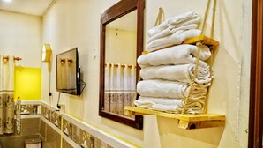 A bathroom with a mirror, a stack of towels, a small trash bin, and a shower curtain. - Sunny Hostel (Can Tho)