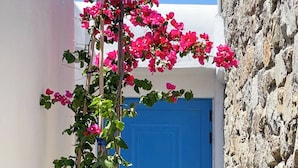 A building with a blue door, white walls, and a stone wall. - Emerald Bay 4BR House with pool by JJ Hospitality (Mikonos)