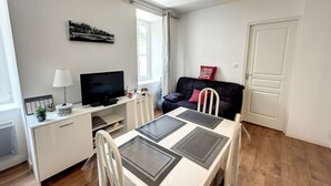 Un espacio habitable compacto con comedor, sofá, televisor y ventana.
