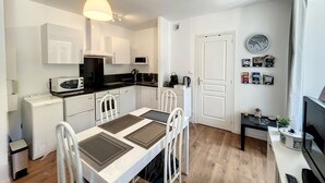 Una cocina compacta con armarios blancos, microondas, estufa y una mesa de comedor con sillas.