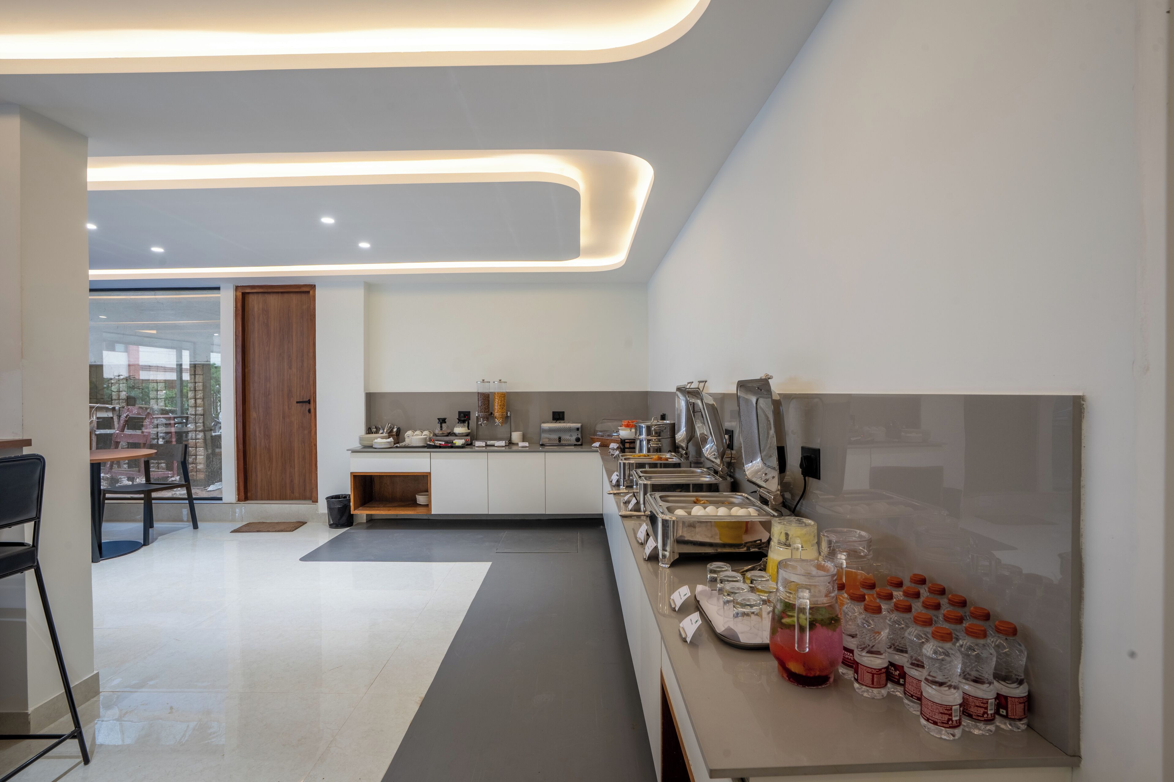 Una cucina moderna con un angolo buffet, che comprende un frigorifero, un lavello e un bancone con generi alimentari e bevande.