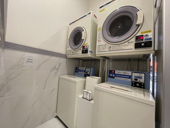 Un área de lavandería con dos lavadoras de carga frontal y una secadora.