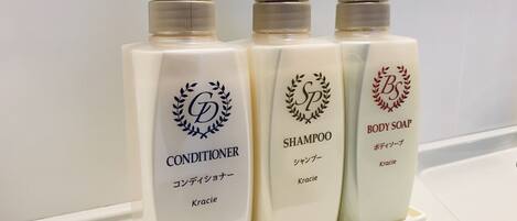 Tres botellas de productos para el cuidado corporal de Kracie: acondicionador, champú y jabón de baño.
