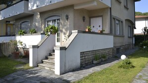 A two-story house with a front porch, steps, and potted plants. - Villetta Adriana, indipendente spaziosaluminosa (Lido di Camaiore)