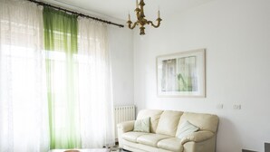 A living room with a beige sofa, a wooden coffee table, a chandelier, and a framed picture on the wall. - Villetta Adriana, indipendente spaziosaluminosa (Lido di Camaiore)