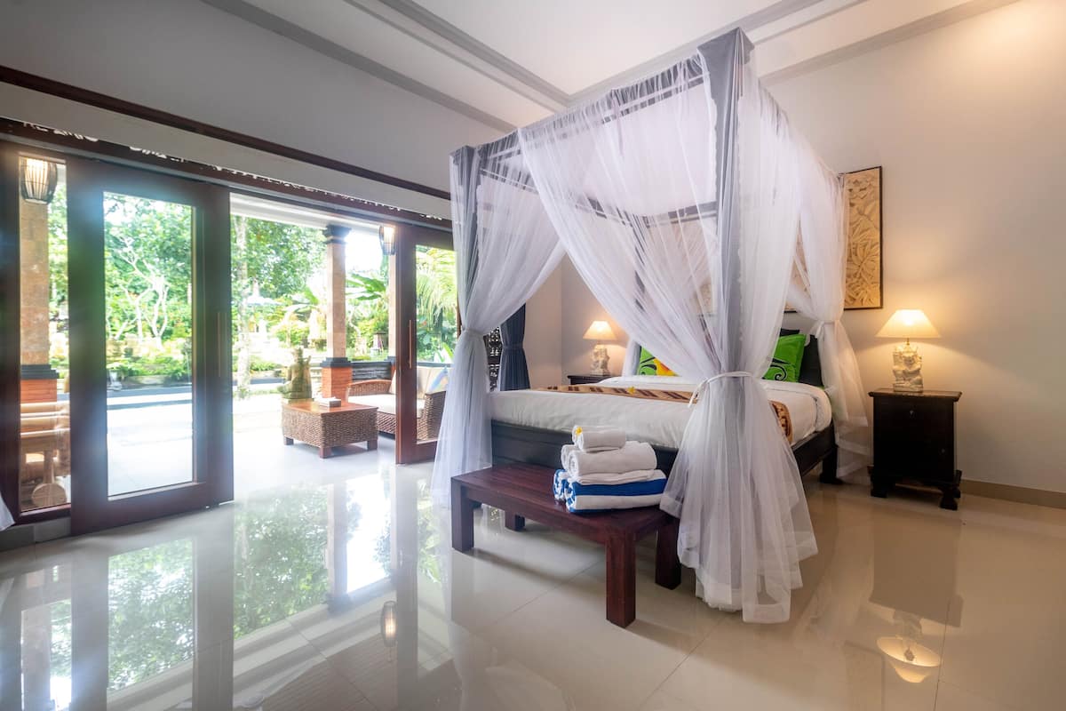 A spacious bedroom with a large bed, a bedside table, and a bench.