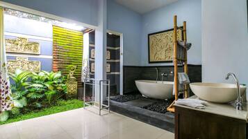 A modern bathroom with a large bathtub, a sink, and a shower area.