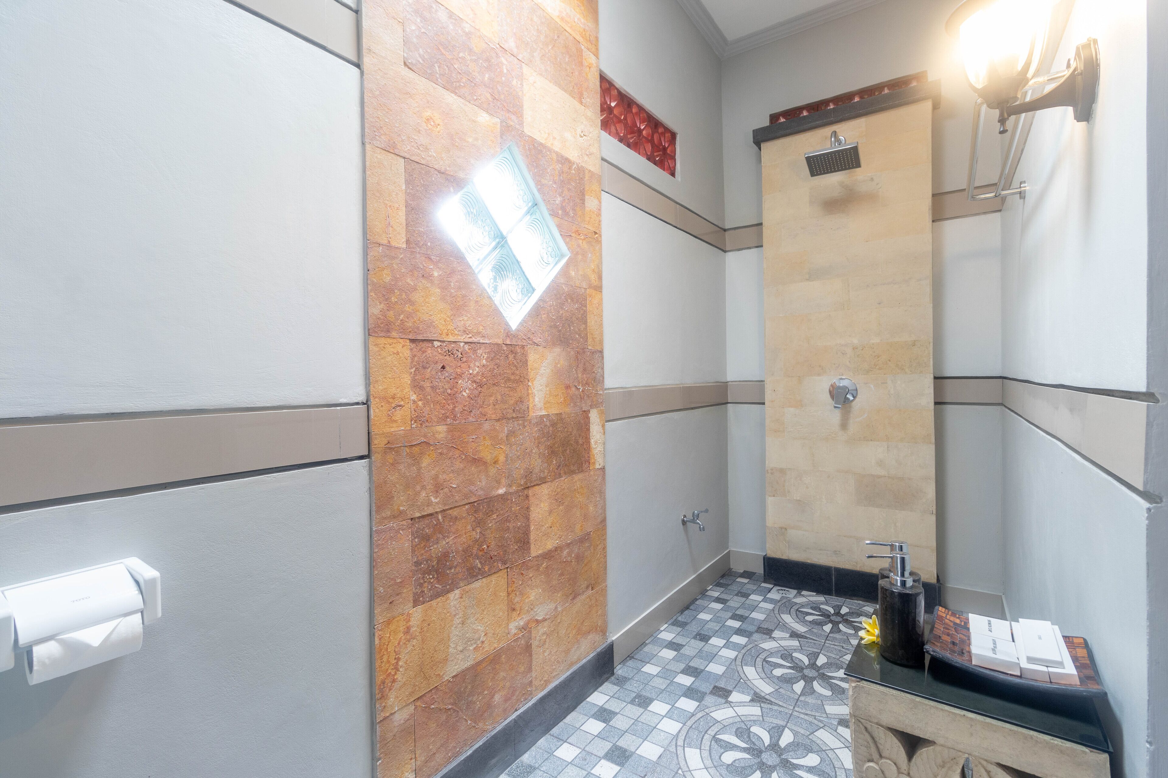 Casa de banho com chão em azulejo, zona de chuveiro e toucador com espelho.