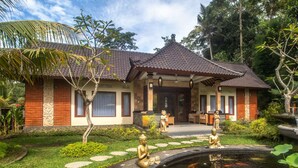 A traditional house with a tiled roof, a front garden with a pond, and statues. - Asli Bali Villa (Bangli)
