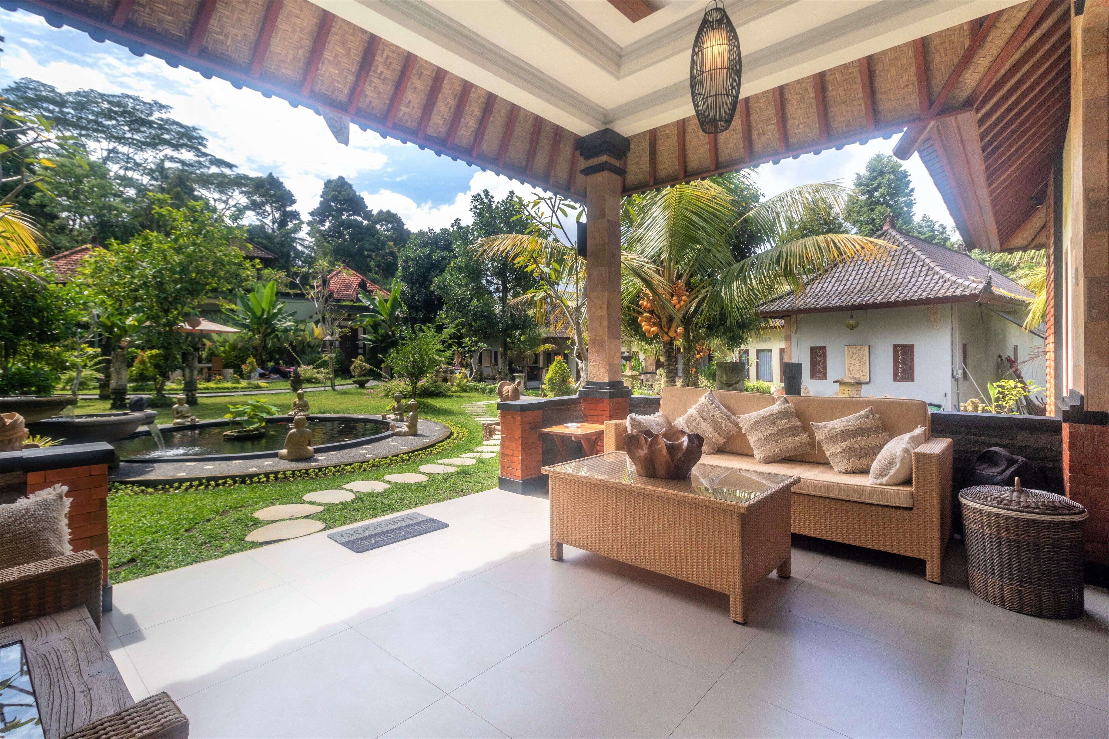 A covered outdoor area with a wicker sofa, a small table, and a decorative fountain.