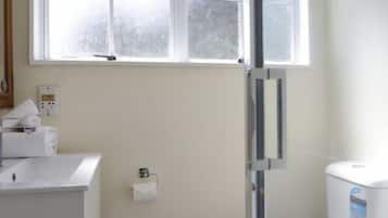 A small, clean bathroom with a white sink, toilet, and window above the toilet.