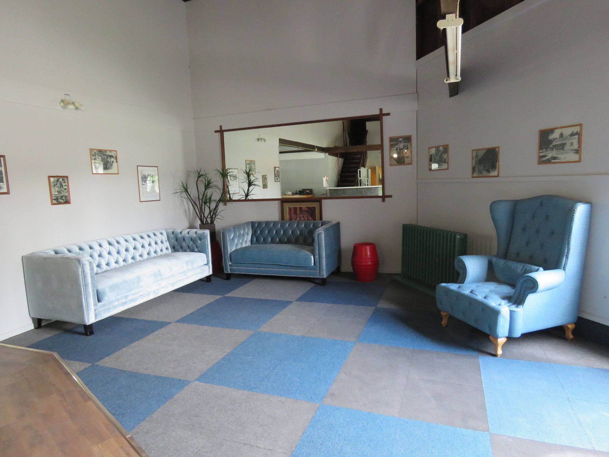 Una sala de estar con piso a cuadros, un sofá, un sillón y un espejo en la pared.