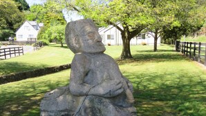 Une sculpture en pierre représentant une figure assise, située dans un parc.