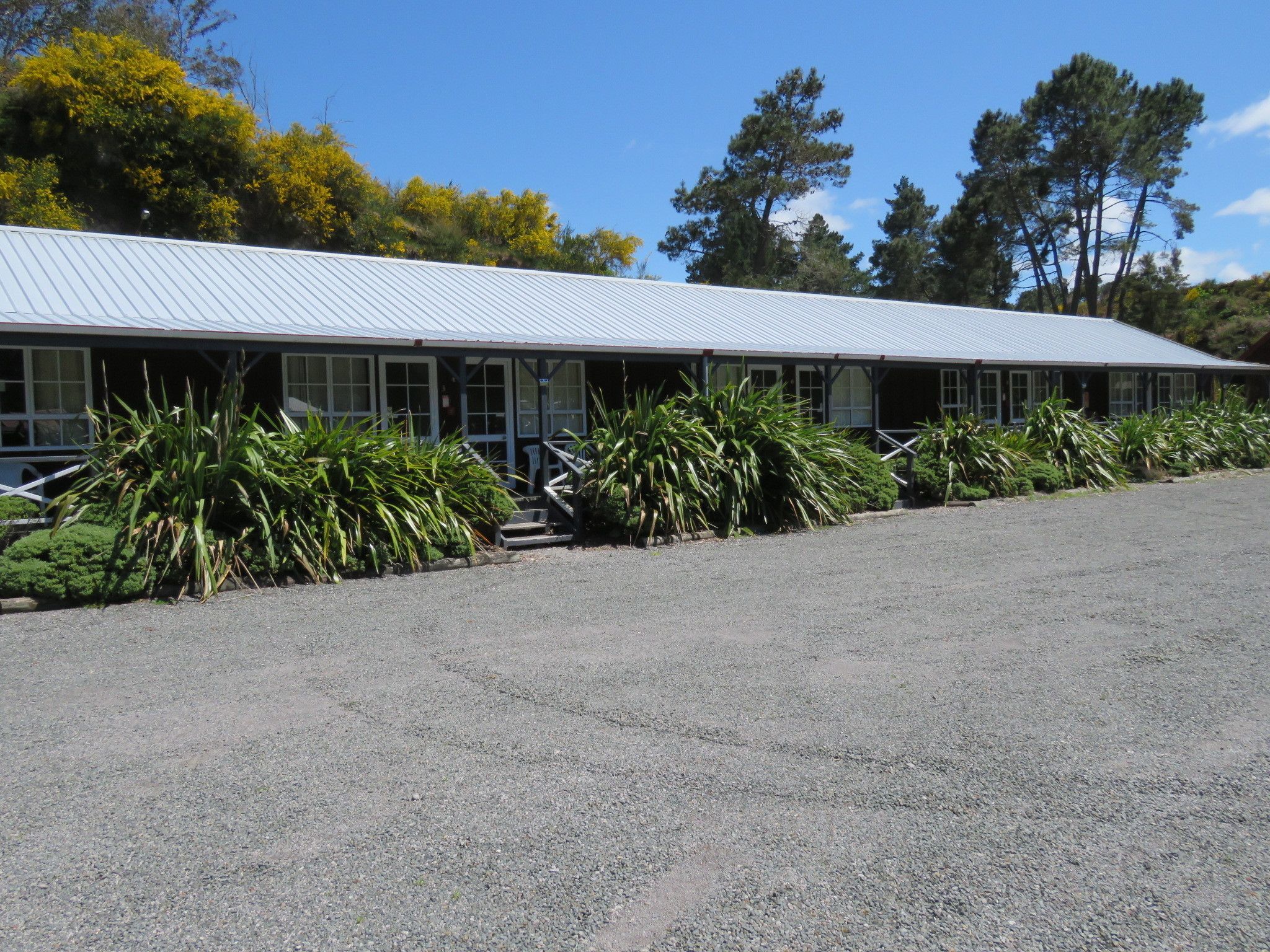 A building with a long, flat roof and a gravel driveway.