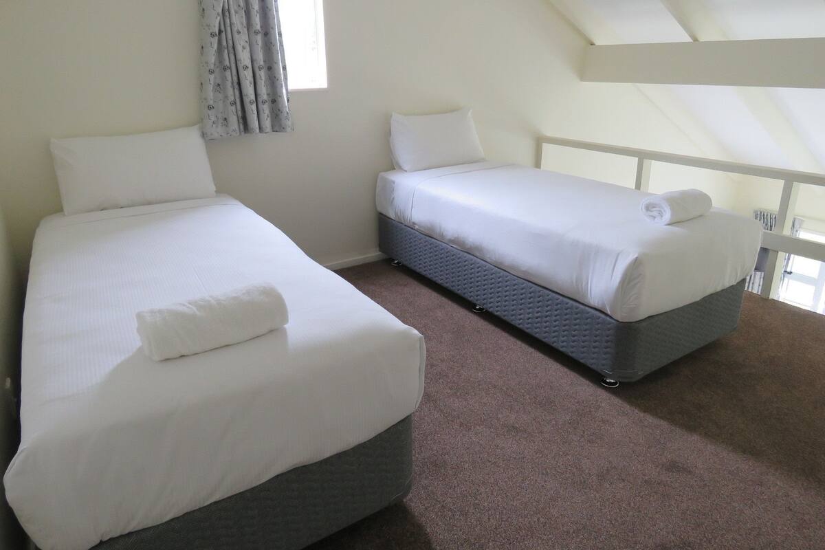 Une chambre avec deux lits, une fenêtre avec des rideaux et un balcon.