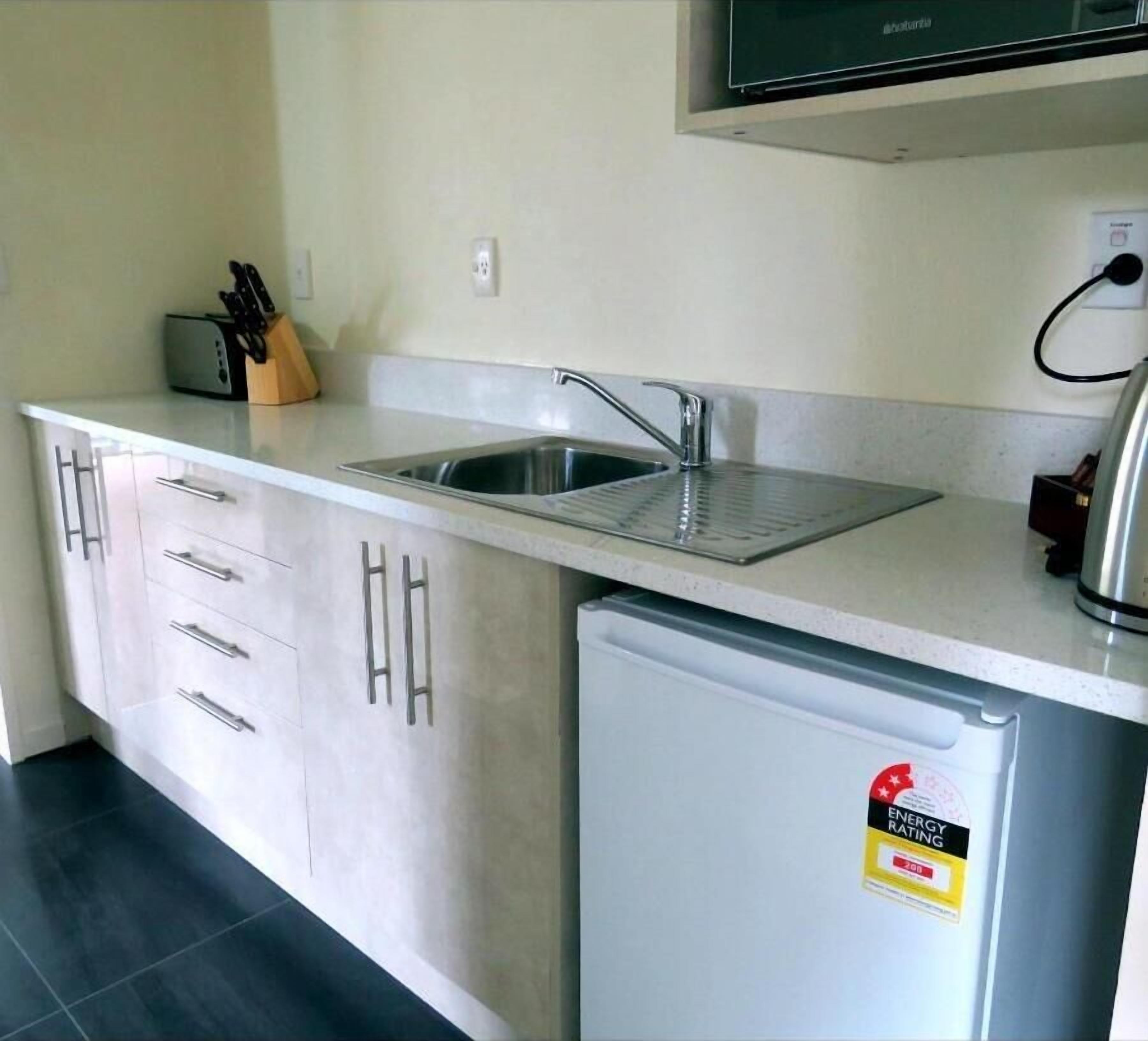 A compact kitchen with a sink, a small refrigerator, and a microwave.