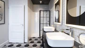 A modern bathroom with two white sinks, a large mirror, and a geometric patterned floor.