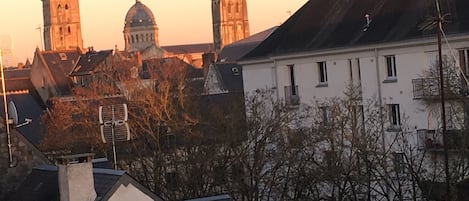 A cityscape with historic buildings, including a prominent tower and a dome structure, under a sunset sky.