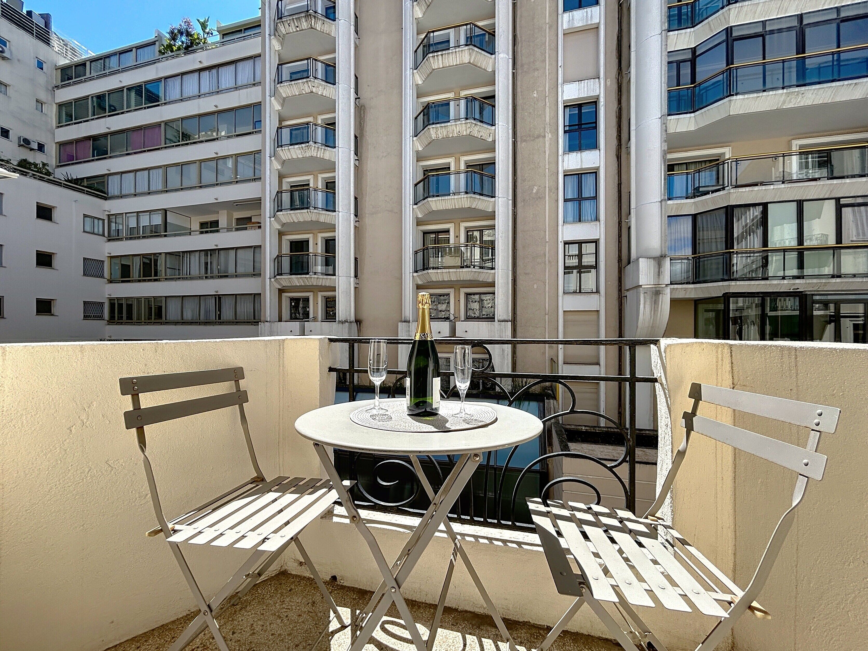 A balcony with a table and chairs, a bottle of champagne, and a glass.