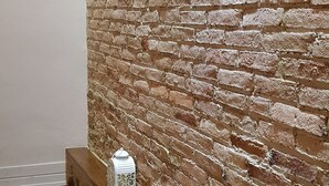 Una escala amb barana de fusta i mur de maó.