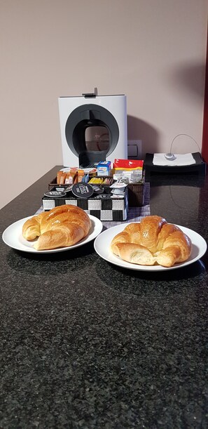 Two plates of croissants on a kitchen counter with a coffee maker and various food items in the background. - A Casa da Igrexa (Ribadavia)