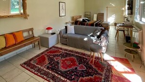 A spacious living room with a large rug, a sofa, a bench, and a dining area with chairs and a table. - Apartment with Garden View (Lecce)