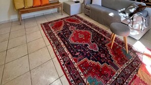 A living room with a sofa, a bench, a rug, and a wall-mounted mirror. - Apartment with Garden View (Lecce)