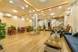Un vestíbulo amplio con piso de madera, una mesa de recepción, una escalera y zonas de estar.