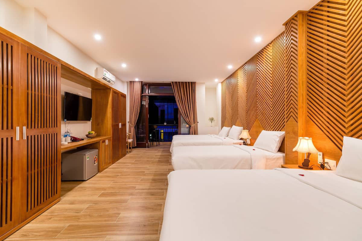 A hotel room with two beds, a TV, a minibar, and a view of the bar area.