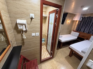 Habitación de hotel con cama, una mesita, espejo, secador de pelo y zona de ducha.